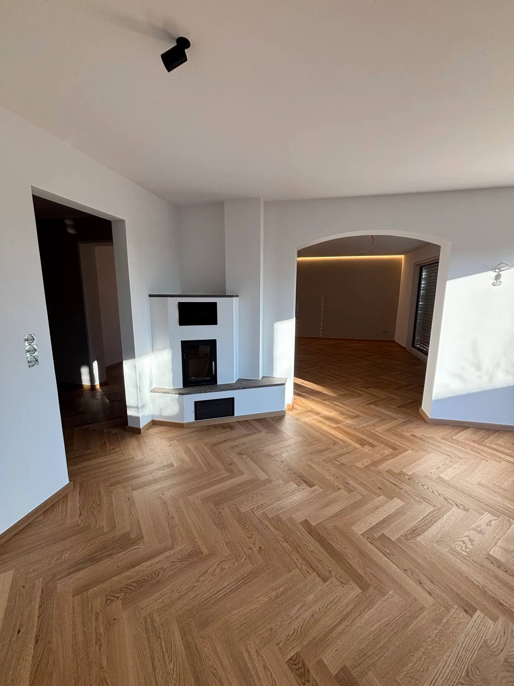Wohnzimmer mit greige gestrichenen Wänden, Eckkamin und Rundbogen