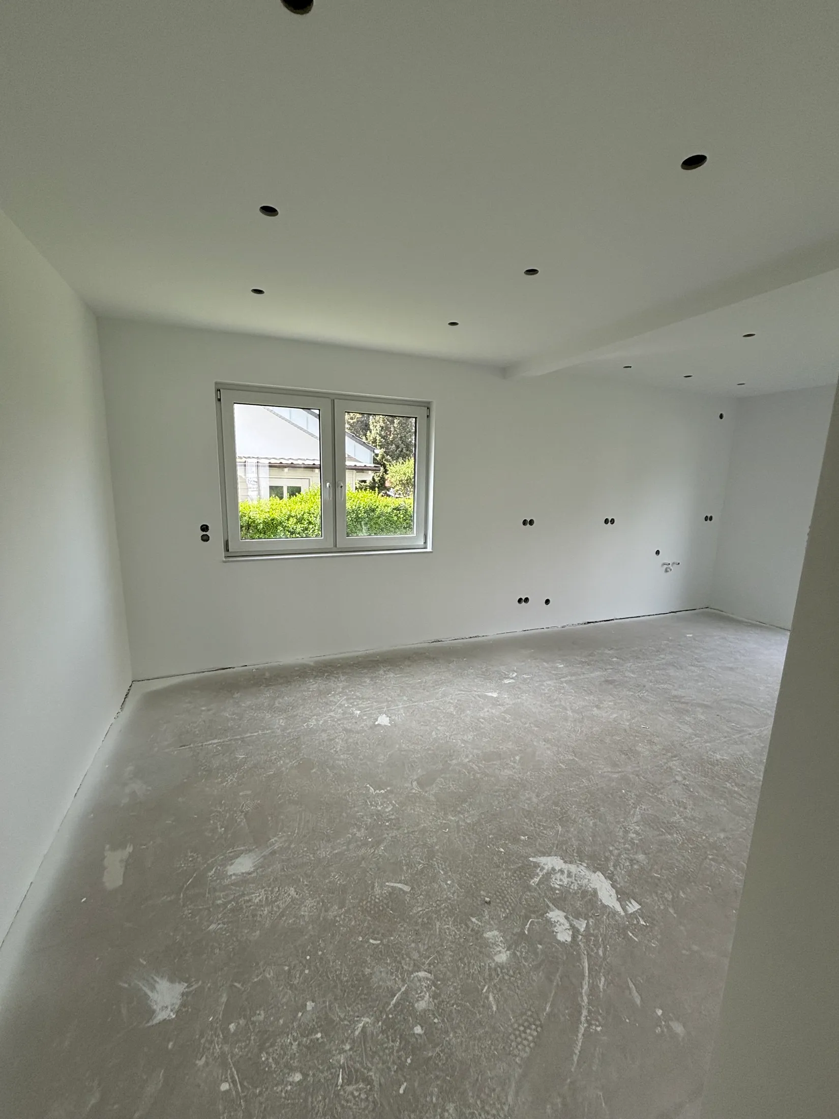 Weiß gestrichener Raum mit neuer LED-Spotdecke und Fenster zum Garten